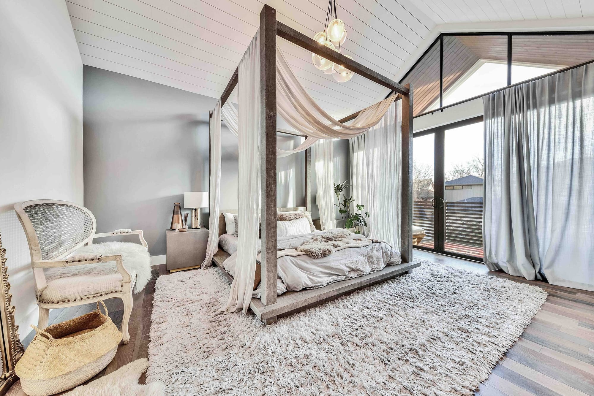 The primary bedroom at The Hether Haus — a four-poster bed draped in sheer canopy under a vaulted white shiplap ceiling