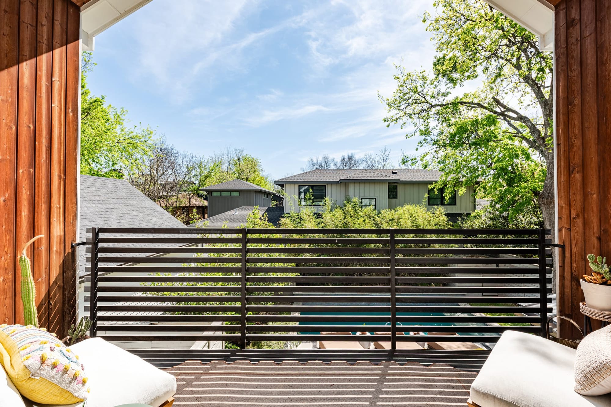 A private balcony behind a cedar-slat privacy screen, its loungers sitting up in the treetops